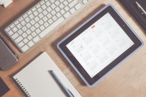 Tablet z kalendarzem obok klawiatury i notatnika