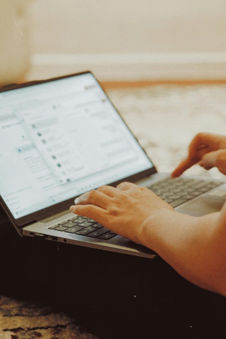 Dłonie na klawiaturze laptopa z otwartą skrzynką pocztową na ekranie